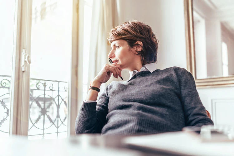 Frau sitzt in einem wei&szlig;en raum und schaut aus dem fenster
